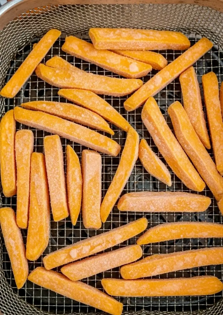 Frozen Alexia sweet potato fries arranged in air fryer basket before cooking