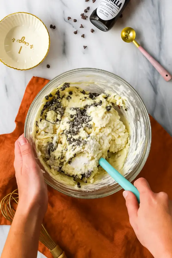 Mixing thick mini muffin batter with chocolate chips using a spatula