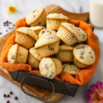 Overflowing basket of mini chocolate chip muffins on wood board