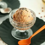 Close-up of red bean ice cream in a glass dessert bowl topped with black sesame seeds