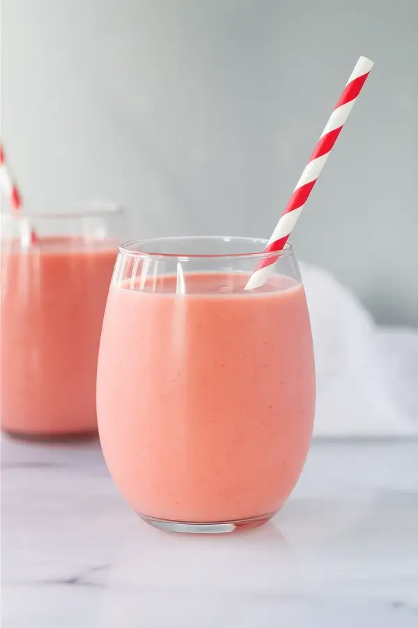 strawberry pineapple smoothie with striped straw in clear glass