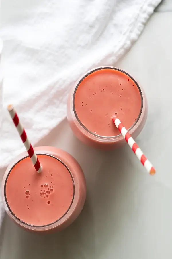 top view of two strawberry pineapple smoothies with straws