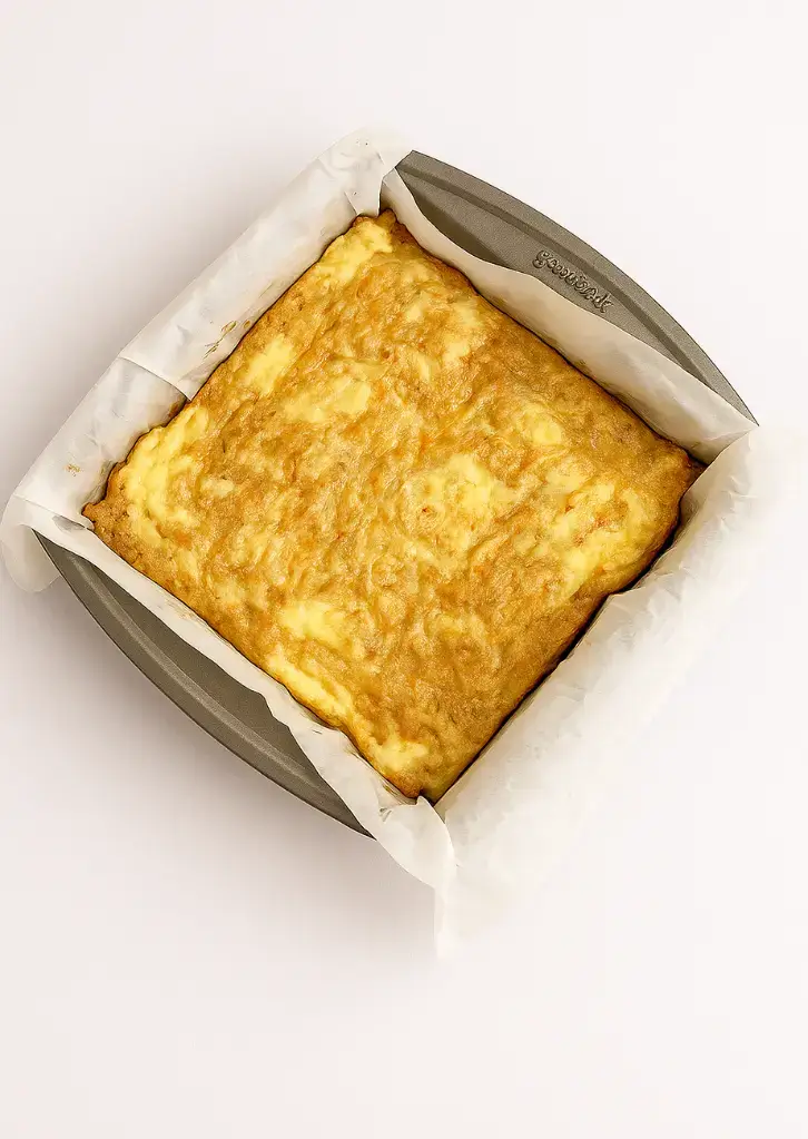 Fully baked carrot cake bars in parchment-lined pan