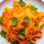 Carrot ribbon salad plated with parsley on a white speckled dish