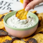 Hand dipping Air Fryer Cottage Cheese Chip into creamy herb dip