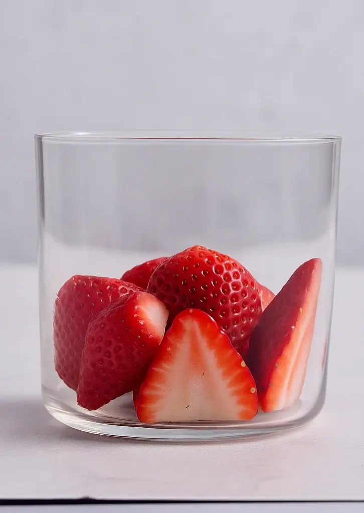 Fresh halved strawberries in a clear cup