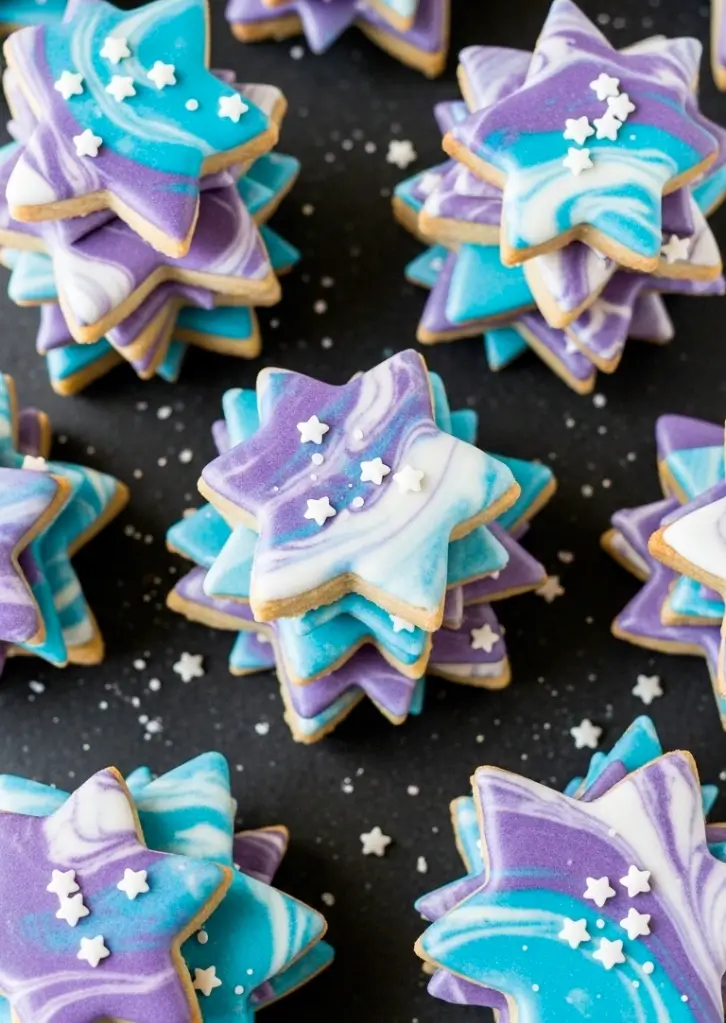Stacks of galaxy star cookies with purple, blue, and white marbled icing
