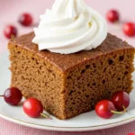 Gingerbread cake slice with whipped cream on white plate