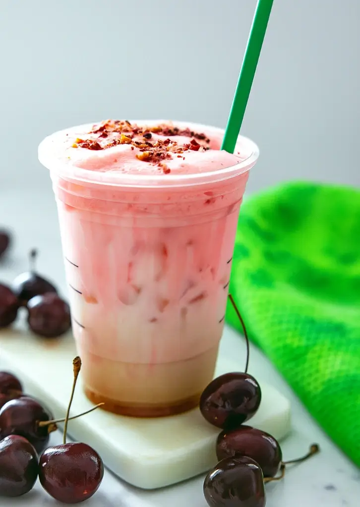 iced cherry chai latte with green straw and foam