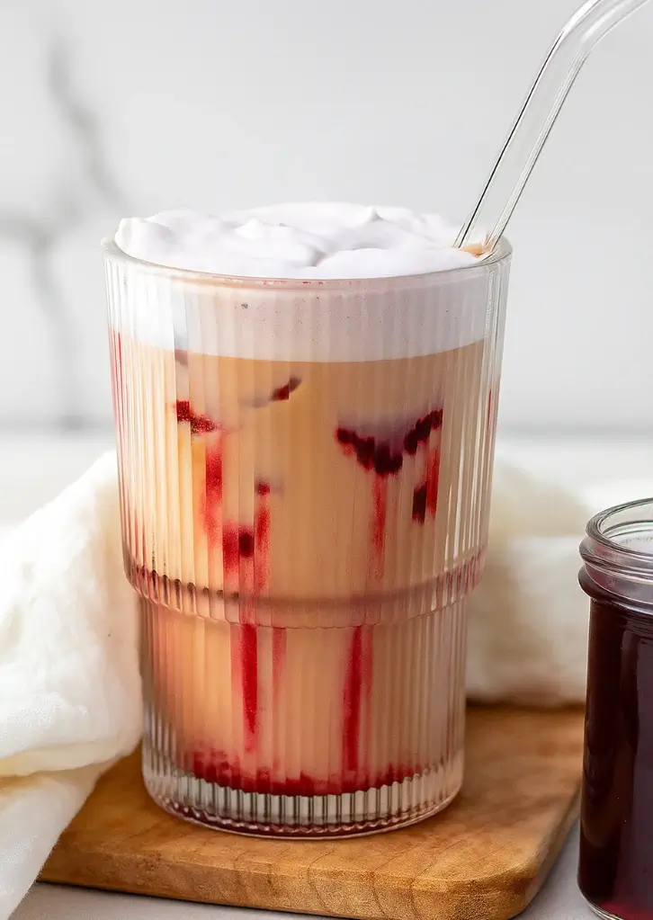 iced cherry chai latte in a glass with visible syrup swirls