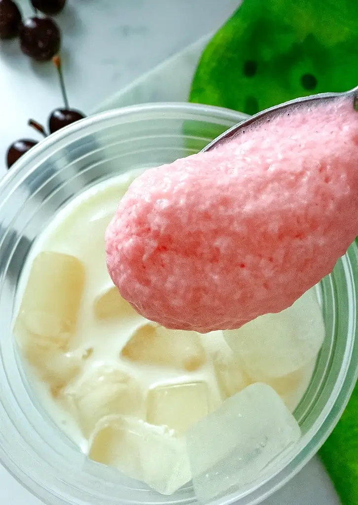 spoon holding cherry cold foam above iced chai drink