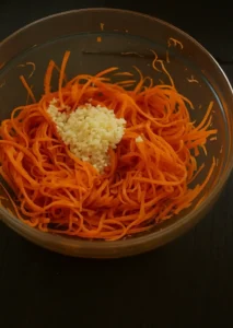 Julienned carrots with minced garlic in a bowl