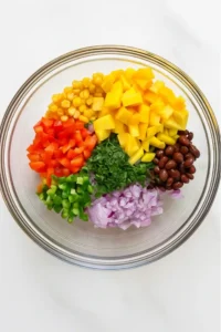 Salad ingredients layered in a glass bowl before mixing