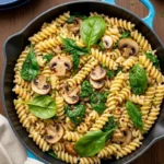 Creamy mushroom and spinach pasta in a skillet with baby spinach and fusilli pasta