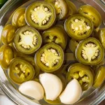 Canned jalapeños and garlic cloves soaking in pickling brine