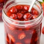 Fresh strawberry jam with visible fruit chunks in glass jar