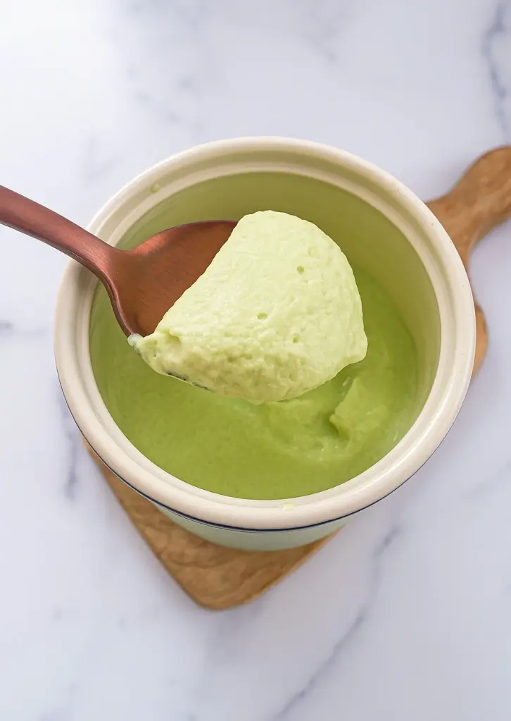 Thick matcha cold foam scooped on a spoon