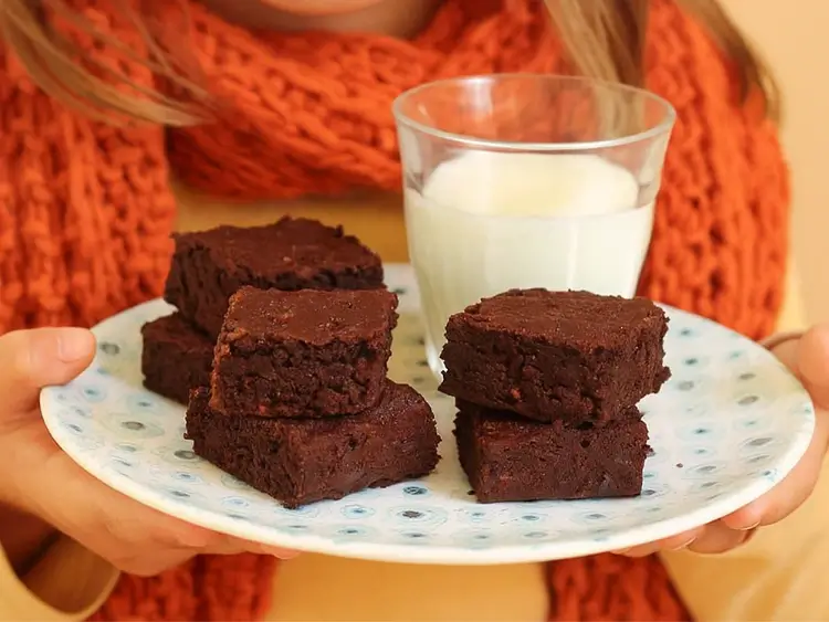 Plate of sweet potato brownies with milk held by sarah
