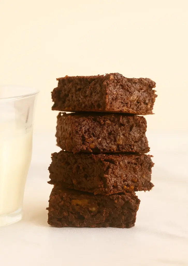 Stack of fudgy sweet potato brownies beside milk glass