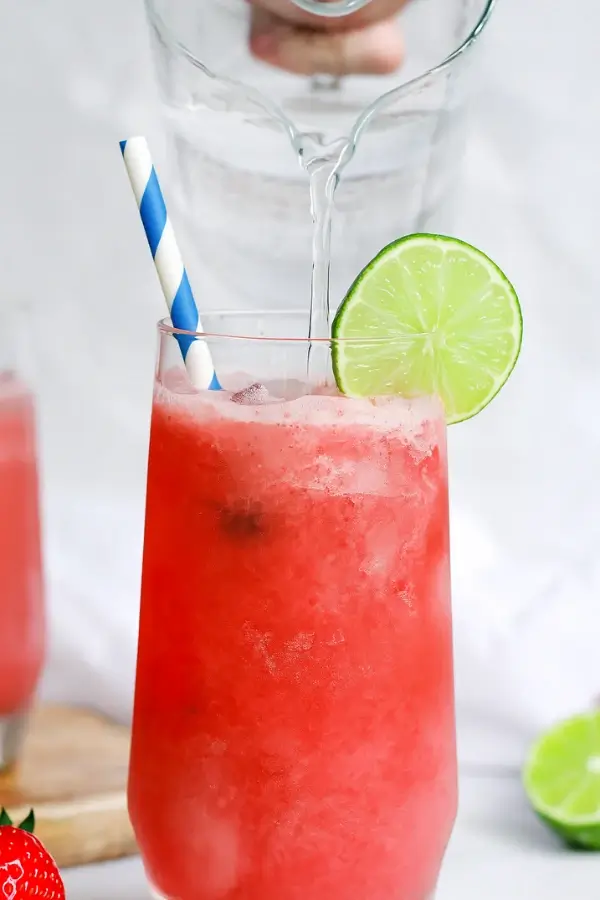 Pouring seltzer into easy virgin strawberry margarita