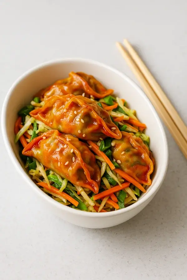 Spicy Korean potstickers over shredded vegetable salad in a white bowl
