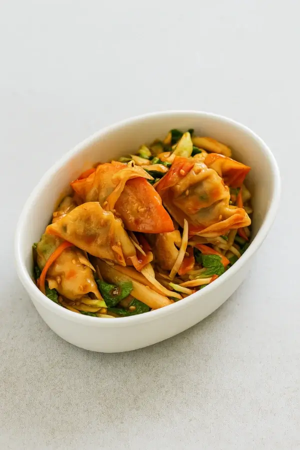 Tossed Bibim Mandu salad in a small oval bowl