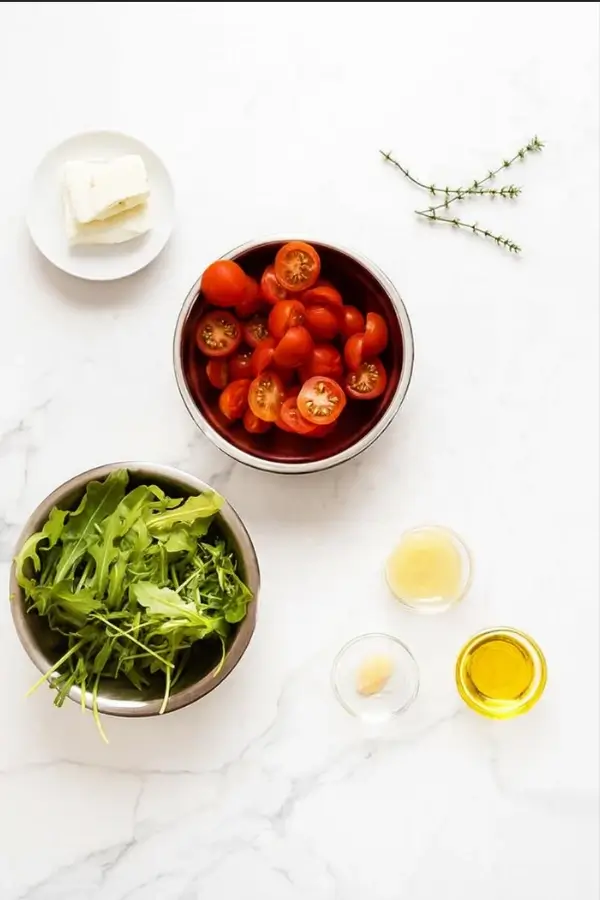 Cherry tomatoes, arugula, feta, and dressing ingredients for salad